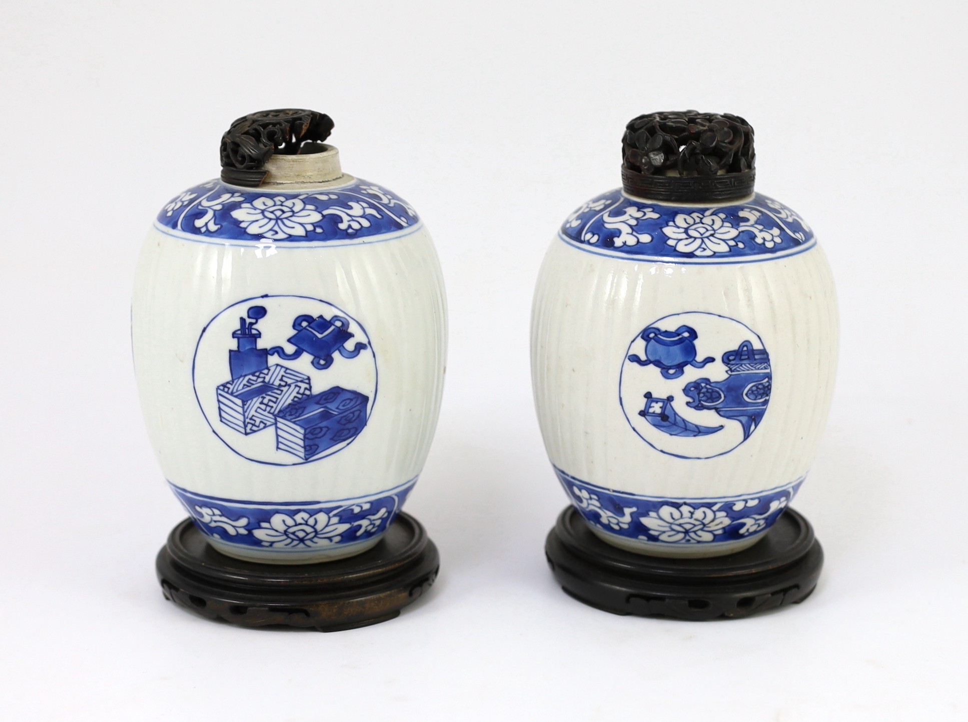 A pair of Chinese blue and white ribbed ovoid jars, Kangxi period, 13.4cm high, excluding wood stand and cover, one chipped with hairline crack